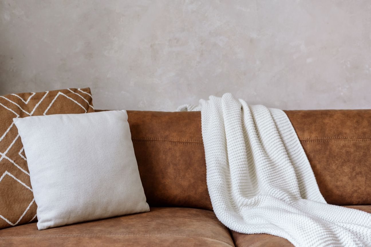 A white throw and cushions on leather sofa