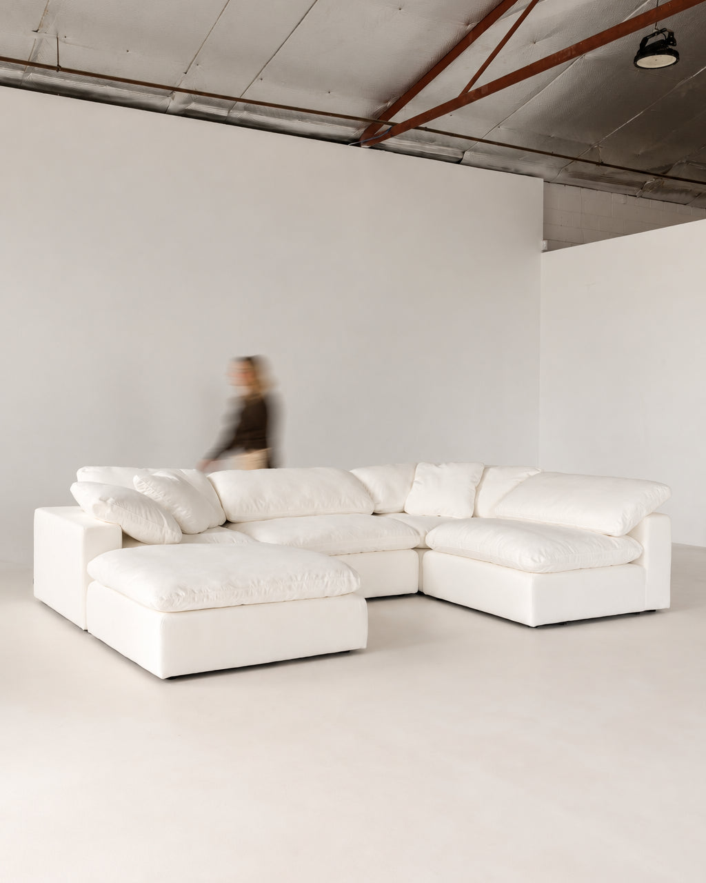Cloud Classic 4-piece modular sofa with ottoman in Warm White, in a bright studio
